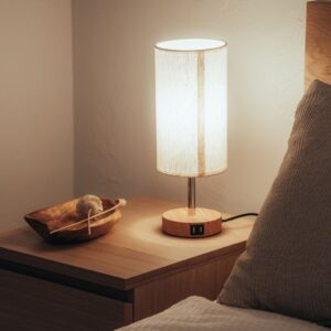 A warm and inviting bedroom scene with a glowing lamp on a wooden nightstand.