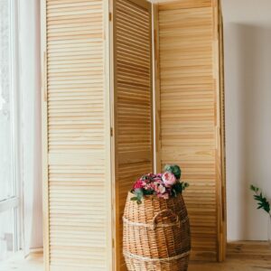 Stylish interior featuring a wooden room divider and decorative basket with flowers.