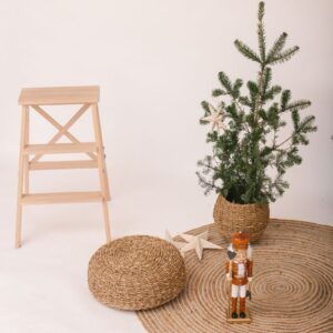 A cozy, minimalist Christmas setup featuring a nutcracker, a small tree, and woven textures in a neutral setting.