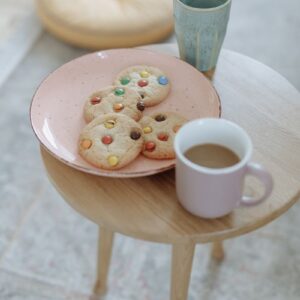 A comforting morning setup with coffee and colorful cookies on a wooden table indoors.