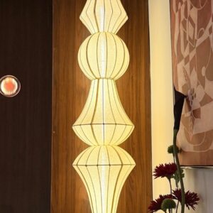 Tall, stacked, illuminated lampshade on wooden wall
