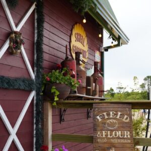 Red barn with "field & flour" sign and flowers.