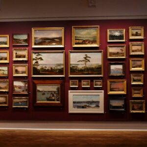 Collection of landscape paintings displayed on a wall.